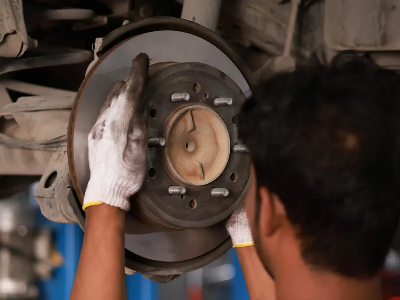 Technician's gloved hands on a brake disc
